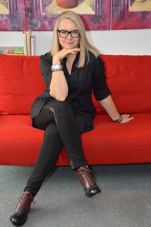PR-Beraterin und Modeflüsterin Stephanie Grupe daheim auf einer roten Couch sitzend (2014)