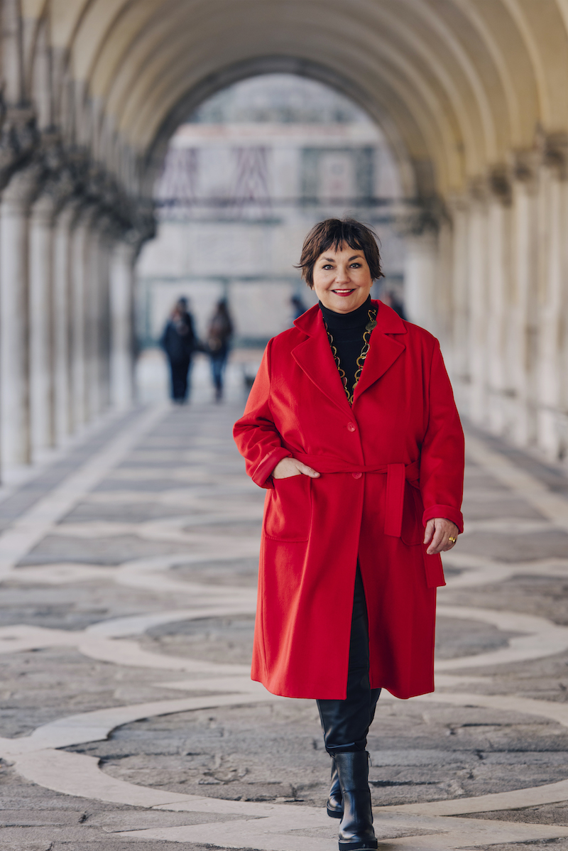 Texterella aka Susanne Ackstaller im roten Mantel auf dem Markusplatz in Venedig.